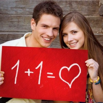 Young couple is holding board with romantic symbol.